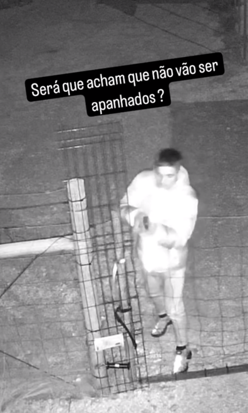 Um dos criminosos a abrir a grade para entrar na propriedade
